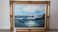 Framed oil painting showing complete seascape with clouds, ocean waves, rocks, and birds.