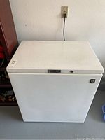 Front view of the white Viking chest freezer showing top opening lid, lock, and power cord plugged into wall outlet.