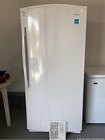 Front view of white upright freezer with manual at base
