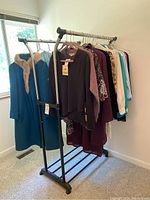 Photo showing the full clothing rack with women's outerwear including a prominent blue coat with fur collar and other assorted jackets and cardigans hung on hangers.