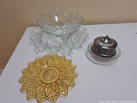 Overview of all items including clear glass punch bowl with glasses, amber serving plate and silver-tone covered bowl on clear glass plate