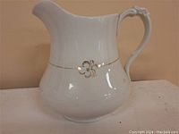 Front view of the antique ceramic pitcher showing clover pattern and gold band