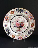 Full view of the round ironstone china plate with floral design and scalloped edge on display stand.