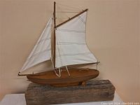 Side view of the vintage wooden sailboat on wooden base showing sails and rigging.