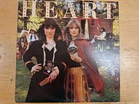 Front cover of Heart's 'Little Queen' LP album showing two women dressed in period style and the album title text with heart symbols.