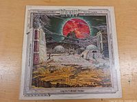 Front cover of Klaatu LP album The Loneliest of Creatures featuring surreal art with red planet and rocky landscape.