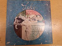 Full front cover of 'Lake' LP showing cat and bathtub scene with water splash border.