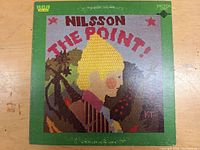 Front cover of the LP vinyl 'The Point' by Nilsson with pixelated art of a blond boy in profile and green border.