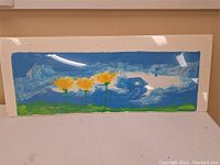 Full view of the paper pulp painting featuring blue sky, green landscape, and three yellow flowers.
