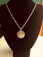 Necklace displayed on black stand showcasing pale pink facetted rose quartz pendant and twisted sterling silver chain.