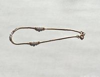 Full view of the delicate gold tone anklet with faux pearl clusters on a white background.