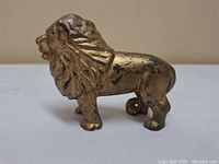 Side view of vintage cast iron lion bank showing bronze finish and detailed mane.