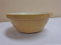 Side angle of the yellow ceramic mixing bowl, showing embossed design and height.
