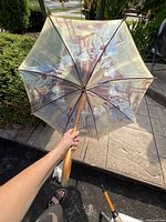 Umbrella held open showing ballerina artwork on inner canopy with wooden handle visible