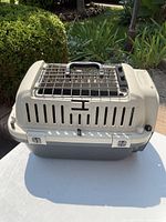 Closed view of beige plastic animal carry case with metal wire door and handle on top.