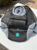 Front side view of black and gray animal carry case backpack with mesh panels and front pocket with paw logo
