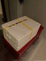 Red cooler in parts with styrofoam insulation box on top, taped and labeled.