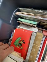 Large bin filled with assorted greeting cards, showcasing a Mickey Mouse Christmas card on top.