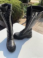 Front and side view of black leather calf height boots showing lace-up closure and side zipper.
