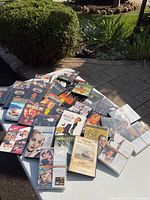Wide view of assorted DVDs spread on a table outside, showing many different titles and colorful cases.