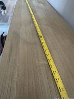 Top view of raw wooden table with measuring tape showing length around 63.5 inches, showing natural wood grain and marks.