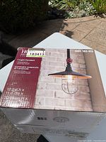 Photo showing the front of the box with image of the industrial style 1-light pendant fixture with cage and bronze finish.