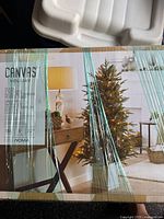Photo of the boxed Canvas Holiday artificial spruce tree with white lights and assembly instructions visible through shrink wrap.