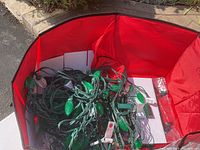 Photo of green bulb string lights tangled inside a red tote.