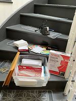 Photo of a variety of office supplies including paper, stickers, stapler, pen, calculator and electric pencil sharpener on stairs