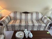 Full view of the damask and striped fabric couch with wooden arms and carved wood crest on backrest.