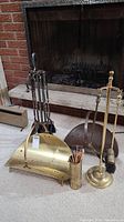 Full view of fireplace tools, log holder, and match holder arranged in front of a fireplace.