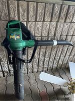 Overall side view of green Barracuda 2595 leaf blower with black collection bag and carrying strap.