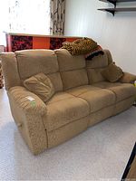 Angled front view of full three-seat recliner sofa with pillows and throws