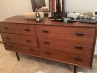 Front view of teak veneer dresser with mirror and objects on top
