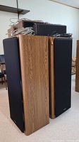 Pair of two tall Technics SB-A52 speakers side by side with cords on top, showing wood veneer sides and black front covers.