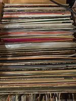 Bird's eye view showing a large quantity of vintage vinyl records stored in a wooden or cardboard container, showing the record spines in a vertical orientation.