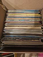 Box filled with a large number of vintage vinyl records stored vertically, showing the variety and quantity in the lot.