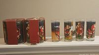 Photo of two boxes containing Coca-Cola glasses with vintage Santa Claus artwork.