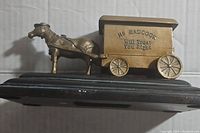 Horse-drawn wagon-shaped coin bank with Badcock branding on black base.
