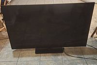 Front view of the Vizio 50-inch television on tiled floor, black bezel and stand visible.