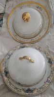 Top view of domed butter dish lids with gold finial knobs on their matching plates