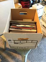 Banker's box full of various vehicle sales catalogues with label on box.