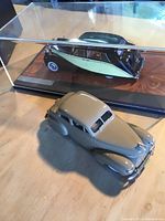 Two die cast model cars, one in display case, shown together on table surface