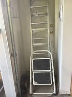 Full view of Caradon Lite extension ladder leaning against wall along with white 2-step ladder in front.