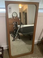 Full frontal view of the large wall mirror showing wood frame and reflective glass.