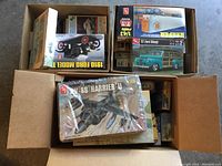 Three open boxes containing various model kits, viewed from above