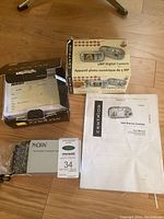 Photo showing Meikai rechargeable NiMH AA batteries and charger in package, Centrios camera box, user manual, and documentation papers.