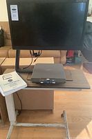 Optelec ClearView C device showing large screen mounted on an adjustable arm above control base with buttons and ports, with manual visible.