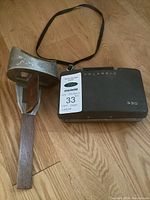 Polaroid Automatic 330 Land Camera with attached carrying strap and vintage viewfinder placed on wooden floor.