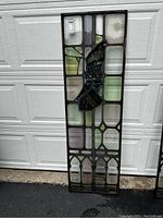 Full front view of antique stained glass window panel showing multicolored glass pieces and metal frame.